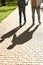 Dad and teenage son walk on pavement in sunny park