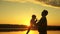 Dad tosses his happy little daughter in air on beach, having fun at sunset. father plays with child by water. happy