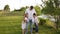 Dad and two children walk together in the green garden near the house.