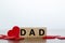 DAD word written on wooden cubes with red hearts around. Father`s day concept