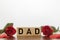 DAD word written on wooden cubes with red hearts and roses around