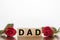DAD word written on wooden cubes with red roses around. Father`s day concept