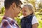 Dad and young daughter pulling faces at each other in a park