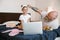 Daddy adjusts headband on head of little girl watching video on large bed at home