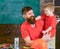 Daddy hugging his kid in workshop. Little boy helping his father to repair details. Bearded man and blond child in same