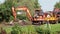 Daewoo industrial digger moving a concrete slab into position with a male worker on