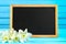 Daffodils flowers and blank blackboard label on wooden background, copy space.