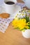 Daisies and dandelions, a cup of coffee and a cookie on a wooden table