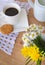 Daisies and dandelions, a cup of coffee and a cookie on a wooden table
