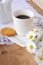 Daisies and dandelions, a cup of coffee and a cookie on a wooden table