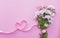 Daisy bouquet and heart shaped ribbon, on pink background