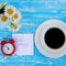 Daisy flowers, alarm clock and cup of coffee