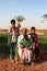 Dakhla Oasis, Egypt - April 2nd of 2015: A bedouin family posing in front of the camera with their own land backwards.