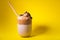 Dalgona coffee with chocolate chips and bamboo straw on yellow background. Korean iced coffee. Copy space