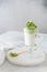 Dalgona Matcha Green Latte, a creamy whipped matcha in a glass on light background. Side view, copy space. Matcha recipe, vegan