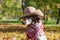 Dalmatian dog in a brown cowboy hat and plaid against the background of yellow autumn fallen leaves