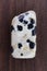 Dalmatian jasper stone texture on brown varnished wood background. Macro closeup