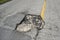 Damaged american road surface with deep pothole. Ruined street in urgent need of repair