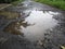 Damaged asphalt road with potholes inundated with water