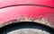 Damaged corroded red car with scratched paint and rust close up
