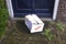 Damaged delivery cardboard box at front door of a house, Fragile package with dents, bad delivery concept