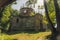 Damaged exposed brick exterior of abandoned church with tower and no roof in green forest. Old christian architecture