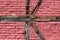 Damaged freshly painted dark red cracked bricks mixed with wooden support beams texture on local train station building wall