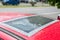 Damaged glass roof window or sunroof on the red car glued with duct tape to prevent water to come in the interior of the vehicle