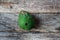 Damaged green avocado on wood background