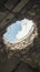 damaged roof hole exposes cloudy sky above Close up