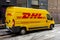 Damaged yellow van of the DHL logistics company with scratches and dents because of not very careful driving in the streets of