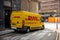 Damaged yellow van of the DHL logistics company with scratches and dents because of not very careful driving in the streets of