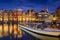 Damrak, Amsterdam, Netherlands. View of houses and boats during sunset. The famous Dutch canals and boats. A cityscape in the even