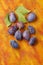 Damson plum (damascene) fruits over painted textile background