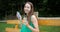 Dance in the park - young girl with headphones sitting on the bench and dancing.