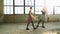 Dance teacher practices classical poses with her student in old factory building