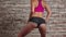 Dance twerk with girl elegant in shorts against a brick wall. Slow motion. Close up