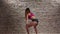 Dance twerk performed by girl in shorts against a brick wall. Slow motion
