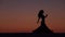 Dancer holds a veil in her hands, she dances a belly dance on the beach. Silhouette