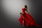 Dancer in Red Dress Jumping. Woman Ballerina Expressive Balance Dance Flying Fabric in Air. Fashion Model Dancing over Gray Studio