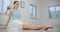 Dancer warms up her legs before rehearsal on the floor of white dance hall, ballet dancer, ballerina in the ballet