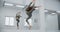 Dancer woman jumps in slow motion infront of mirror wall, gymnastics in the white dance hall, stretching trainer, yoga