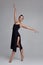 Dancing ballerina in a black dress. Contemporary graceful performance on a gray background.