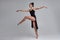 Dancing ballerina in a black dress. Contemporary graceful performance on a gray background.