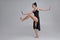 Dancing ballerina in a black dress. Contemporary graceful performance on a gray background.