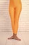 Dancing ballet position of feet. orange. practicing in ballet studio. sport wear fashion. woman in orange leggings on