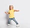 Dancing boogie cool playful kid baby girl in yellow t-shirt is having fun good time pointing at us feeling great