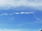 Dancing cloud forming by strip of white cloud against blue sky.