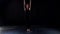 Dancing gymnast woman in dark room, female figure is moving on black background