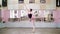 In dancing hall, Young ballerina in black leotard performs 1 arabesque, raises her leg up behind elegantly, standing